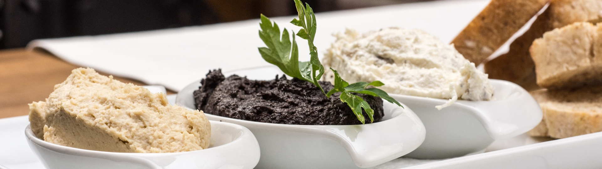 Vorspeisen-Auswahl – Köstliche Häppchen für den perfekten Start Verschiedene kleine Vorspeisen, stilvoll auf Tellern angerichtet, darunter Oliven, Brot und Dips, serviert auf einem rustikalen Tisch – ideal für den Auftakt eines Menüs.