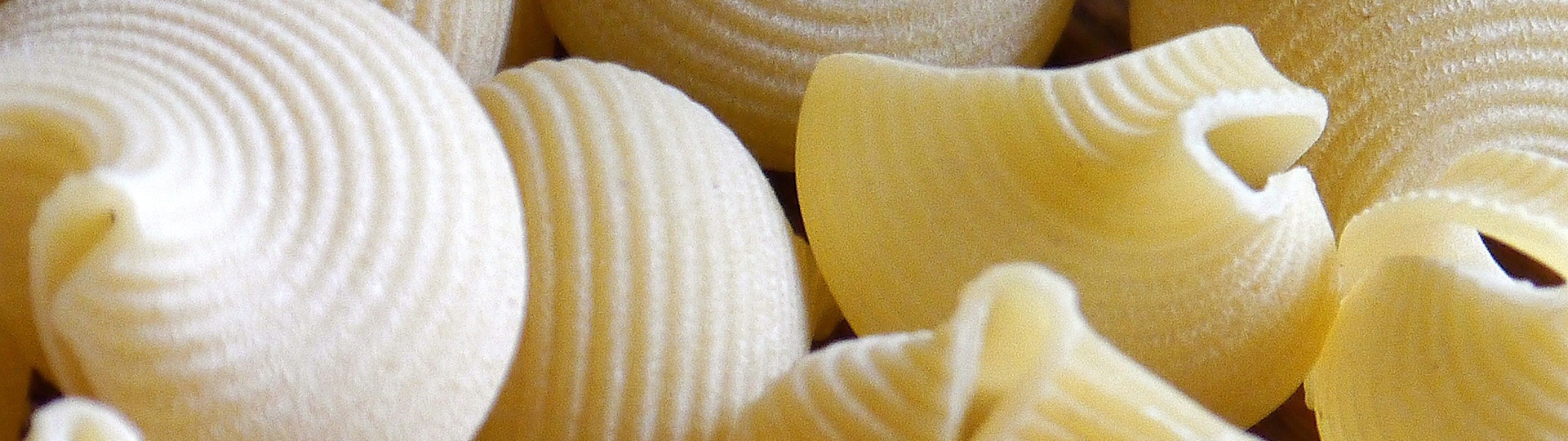 Getrocknete Pasta – Traditionelle italienische Teigwaren Verschiedene Sorten getrockneter Pasta, darunter Spaghetti und Fusilli, kunstvoll auf einem rustikalen Holztisch arrangiert – ideal für klassische Nudelgerichte.