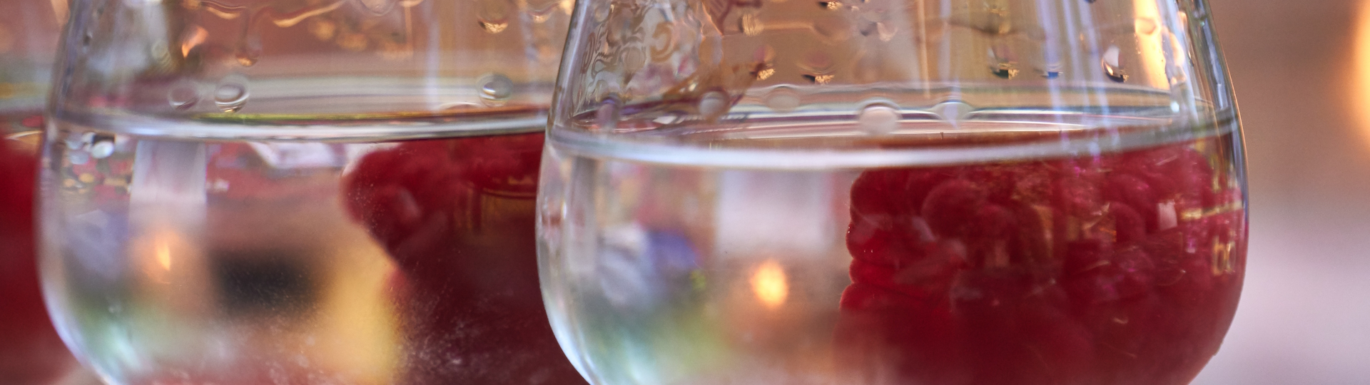 Himbeergeist mit frischen Himbeeren im Glas Glas gefüllt mit klarem Himbeergeist und frischen Himbeeren, elegant präsentiert vor einem rustikalen Hintergrund, symbolisierend die Frische und Qualität des edlen Obstbrands.